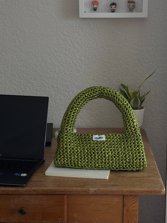 Handgemachte grüne metallic Häkeltasche im Loaf-Design von Chellibe Studio, zeigt feine Handarbeit und glänzendes Garn, stilvolles nachhaltiges Accessoire
